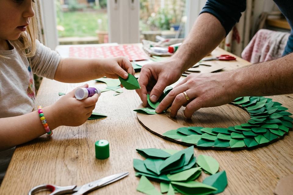 Les mains posent le premier rang de feuilles de papier vert collées en écailles sur l'anneau de carton