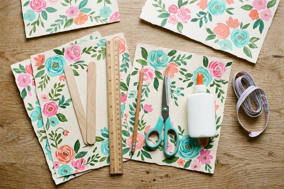 Le matériel à plat : feuilles de papier décoré, bâtonnets de bois, règle, crayon papier, ciseaux, colle et ruban