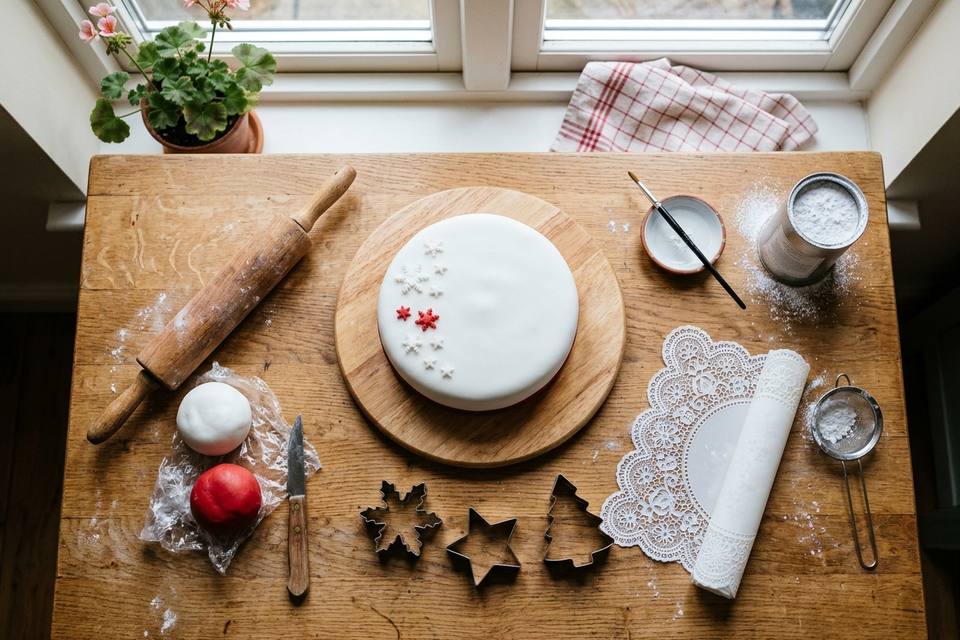 Le matériel à plat : un gâteau garni, pâte à sucre blanche et rouge, rouleau, emporte-pièces, tapis à dentelle, couteau et planche